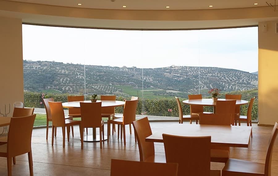 tasting room at Boutari Crete Winery with a wall glass through which you see vineyards and mountains outside